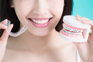 Patient Holding Clear Aligner And Braces Model Showing Average Invisalign Treatment Time