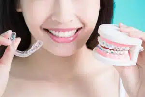 Patient Holding Clear Aligner And Braces Model Showing Average Invisalign Treatment Time